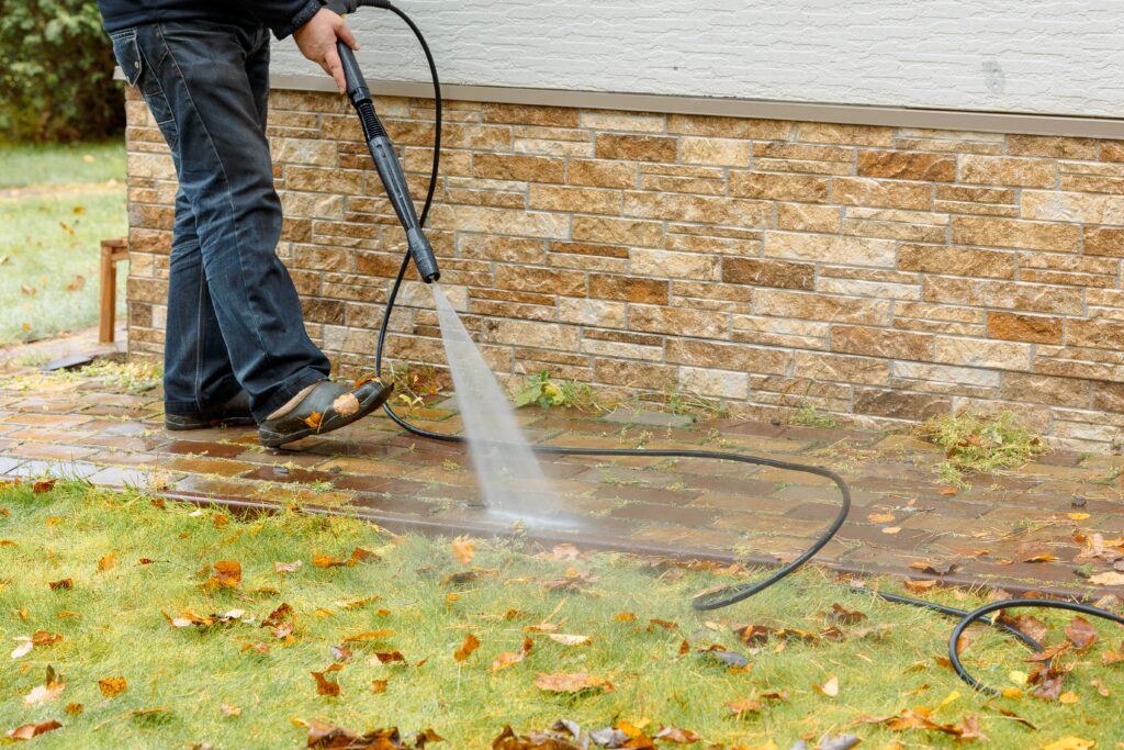 man-cleaning-street-with-high-pressure-power-washer-washing-stone-garden-paths-min