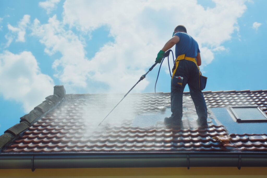 man-cleaning-weathered-tile-roof-blue-sky-min